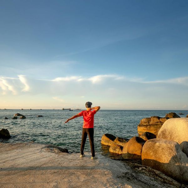 Silhouette of a person stretching at sunrise, representing energy.